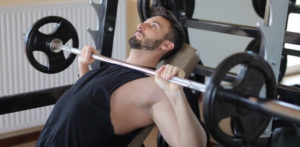 a man performing an incline barbell bench press at the gym